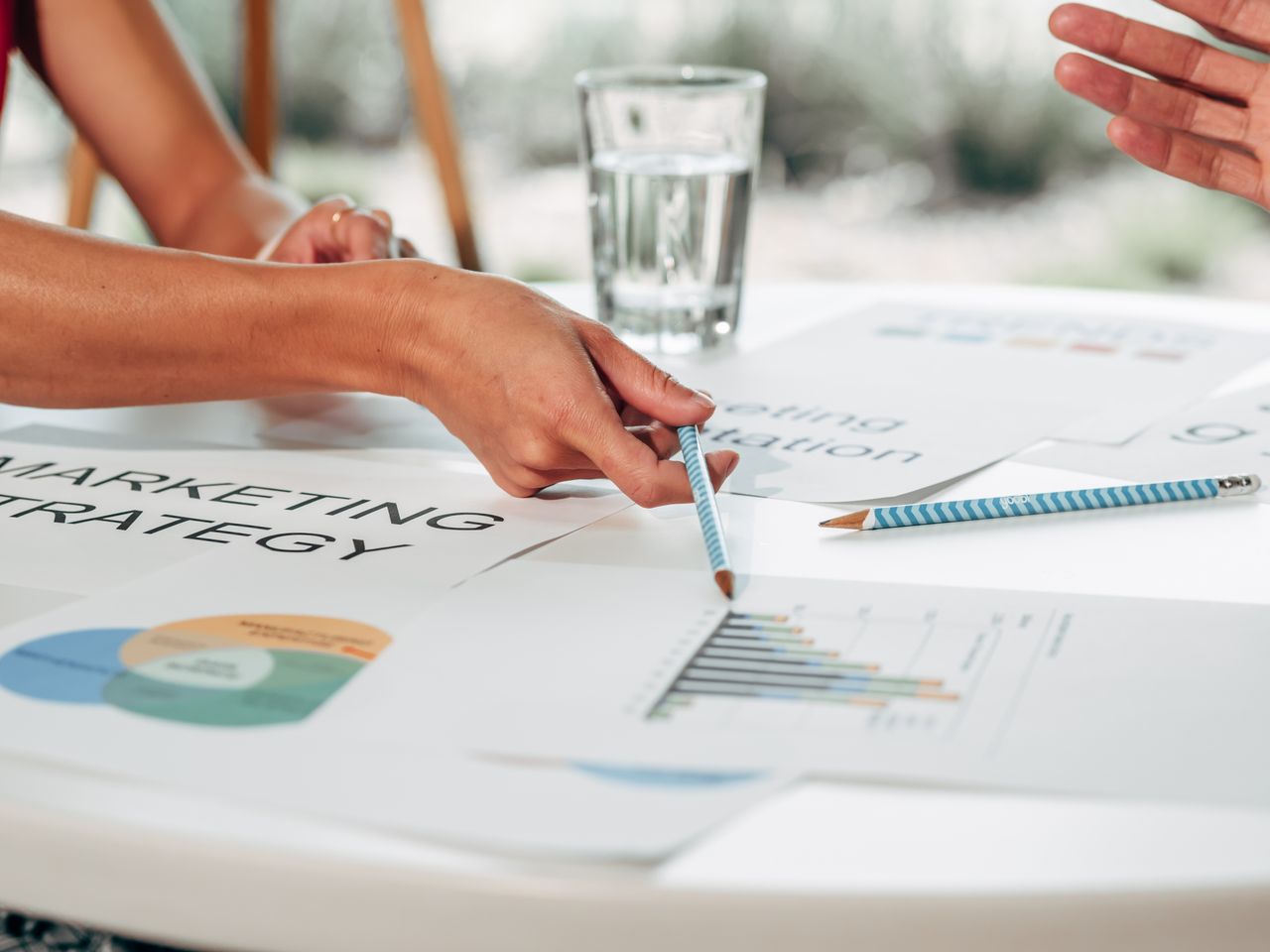Mains en train d’échanger au sujet d’une stratégie marketing, avec des graphiques, dans un bureau.